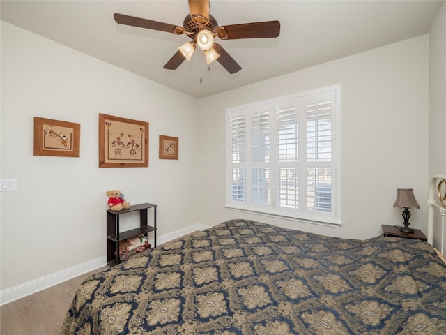 bedroom with a ceiling fan, baseboards, and wood finished floors