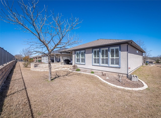 back of property featuring stucco siding, driveway, fence, a yard, and a patio area