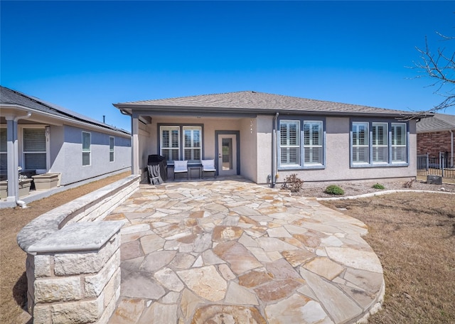 rear view of property featuring stucco siding and a patio