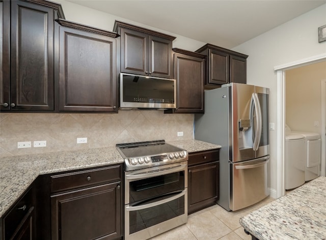 kitchen with tasteful backsplash, dark brown cabinets, washing machine and dryer, light tile patterned floors, and appliances with stainless steel finishes