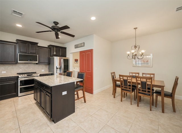 kitchen with tasteful backsplash, visible vents, decorative light fixtures, ceiling fan with notable chandelier, and appliances with stainless steel finishes