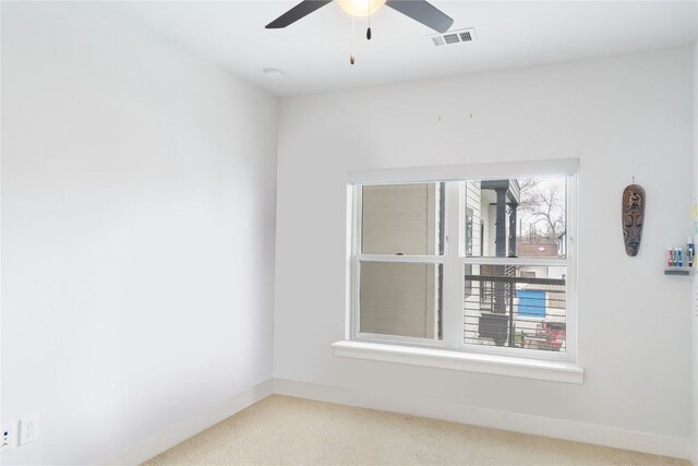 empty room with baseboards, visible vents, carpet floors, and ceiling fan