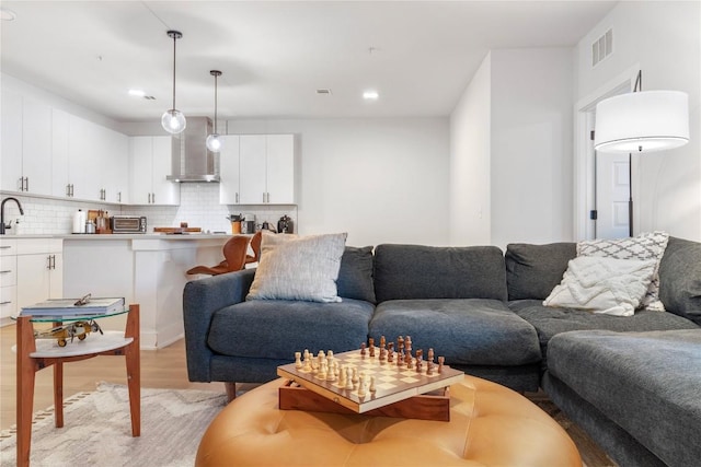 living room featuring light wood-style flooring, a toaster, recessed lighting, and visible vents