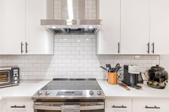 kitchen with decorative backsplash, light countertops, wall chimney range hood, and stainless steel range with electric stovetop