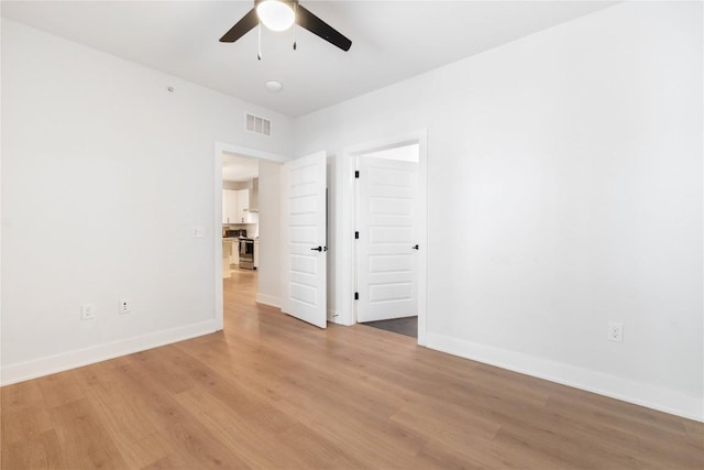 empty room with light wood-type flooring, baseboards, visible vents, and a ceiling fan