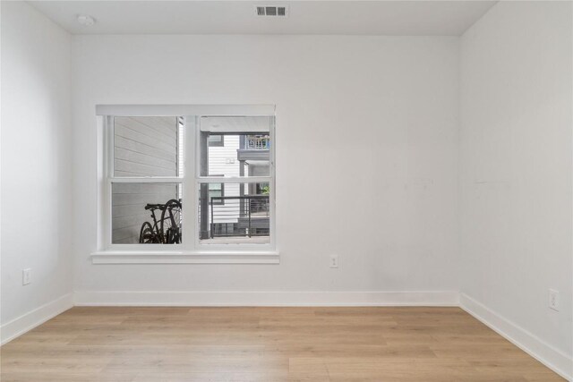 spare room featuring visible vents, light wood-style flooring, and baseboards