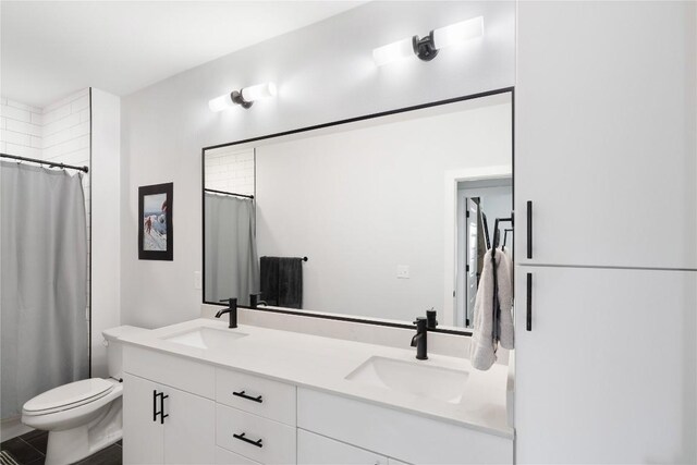 full bathroom with double vanity, toilet, a shower with shower curtain, and a sink