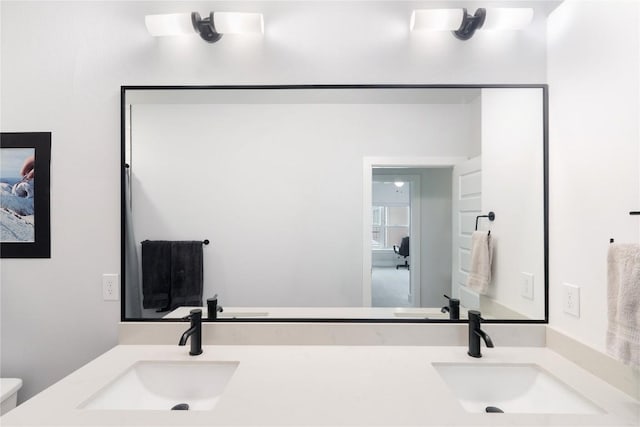 bathroom with double vanity, toilet, and a sink