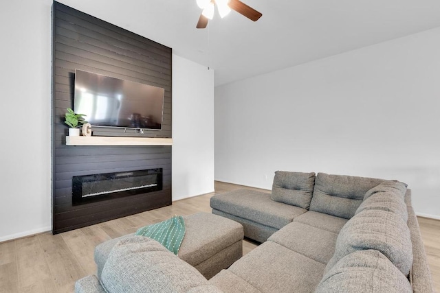 living room with a fireplace, baseboards, ceiling fan, and wood finished floors