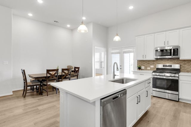 kitchen with a sink, light wood-style flooring, tasteful backsplash, and stainless steel appliances