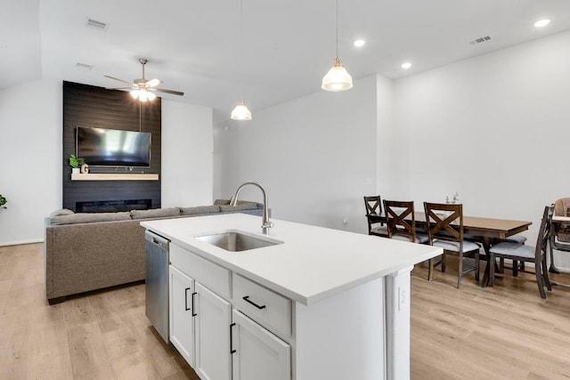 kitchen with visible vents, a sink, light wood-style floors, stainless steel dishwasher, and a large fireplace