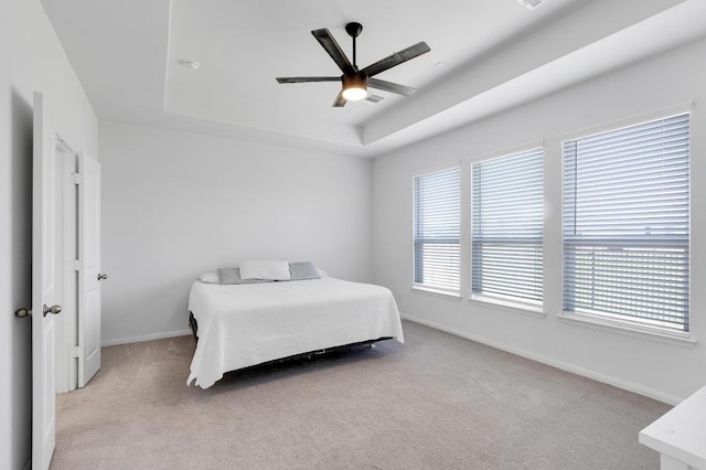 bedroom featuring a tray ceiling, carpet floors, baseboards, and ceiling fan