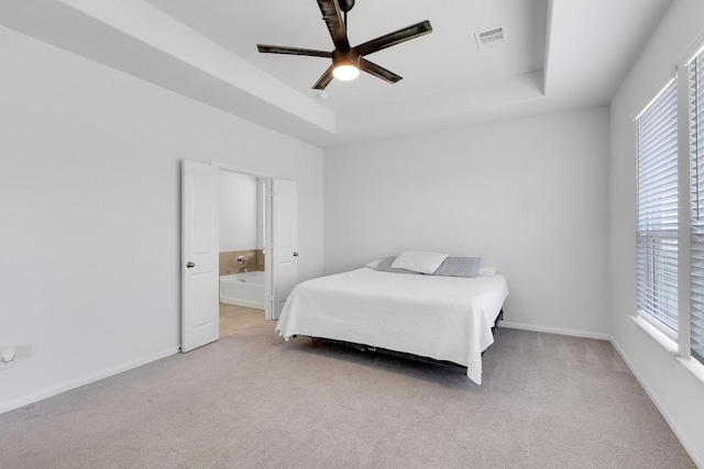 bedroom with a tray ceiling, baseboards, light colored carpet, and visible vents
