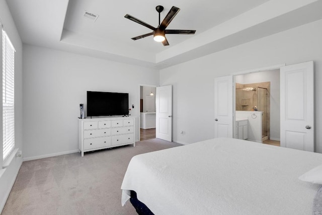 bedroom featuring light carpet, visible vents, multiple windows, and a tray ceiling