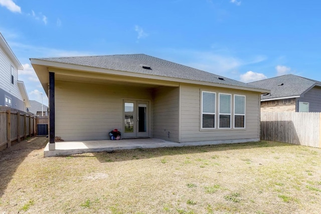 back of house with a patio, a lawn, a fenced backyard, and a shingled roof