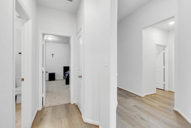 hall featuring light wood-style flooring and baseboards