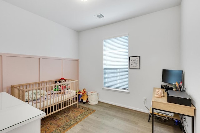 bedroom with visible vents, baseboards, and wood finished floors