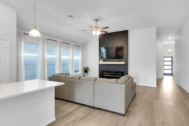 living room with visible vents, lofted ceiling, ceiling fan, light wood-style floors, and a large fireplace