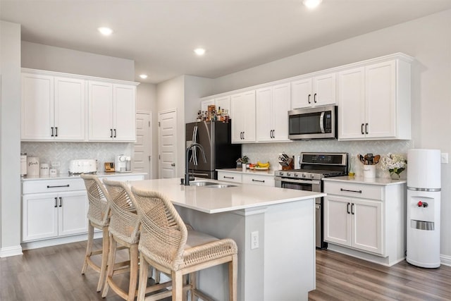 kitchen with a sink, stainless steel appliances, a center island with sink, and white cabinetry