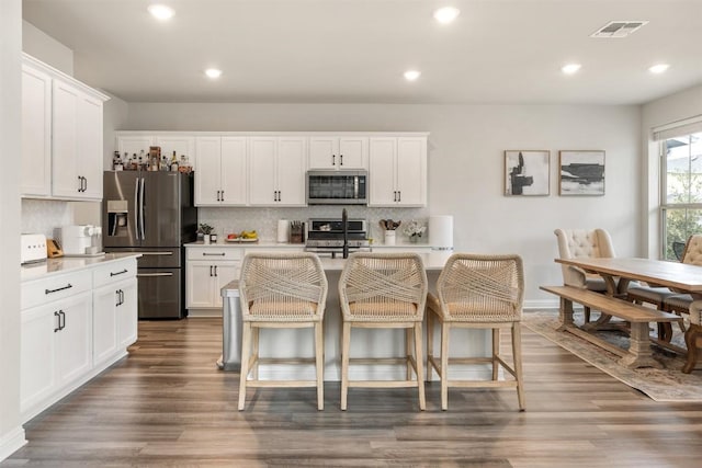 kitchen featuring visible vents, light countertops, dark wood-type flooring, appliances with stainless steel finishes, and tasteful backsplash