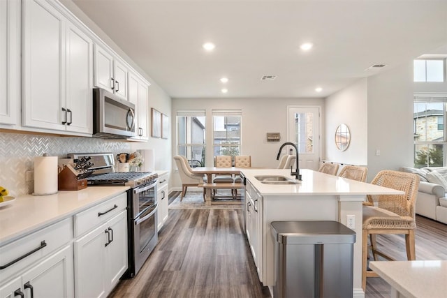 kitchen featuring decorative backsplash, dark wood-style flooring, stainless steel appliances, and a sink