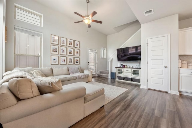 living area with visible vents, a ceiling fan, dark wood-style flooring, baseboards, and stairs