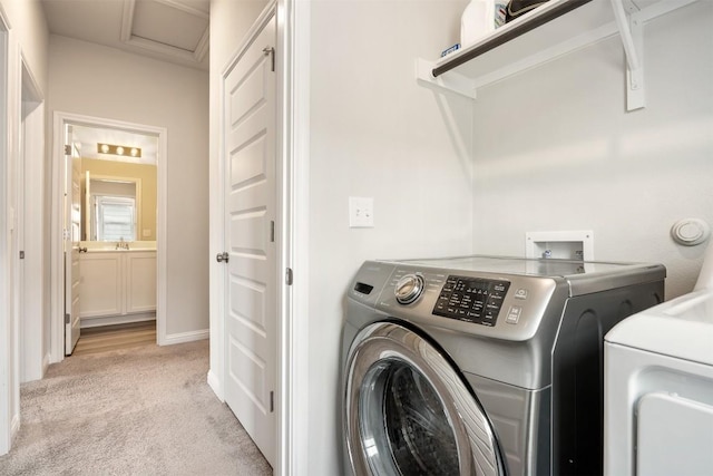 clothes washing area with laundry area, washer and dryer, light colored carpet, and a sink