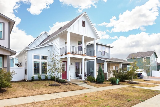 view of front of property featuring a front yard, a balcony, covered porch, and board and batten siding