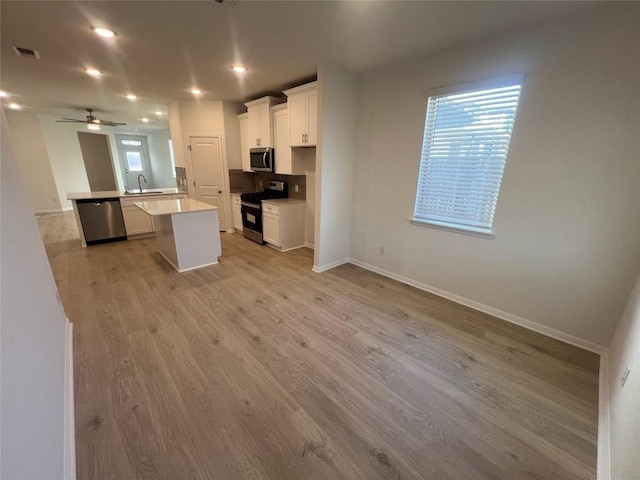 kitchen featuring light wood finished floors, visible vents, stainless steel appliances, white cabinetry, and a sink