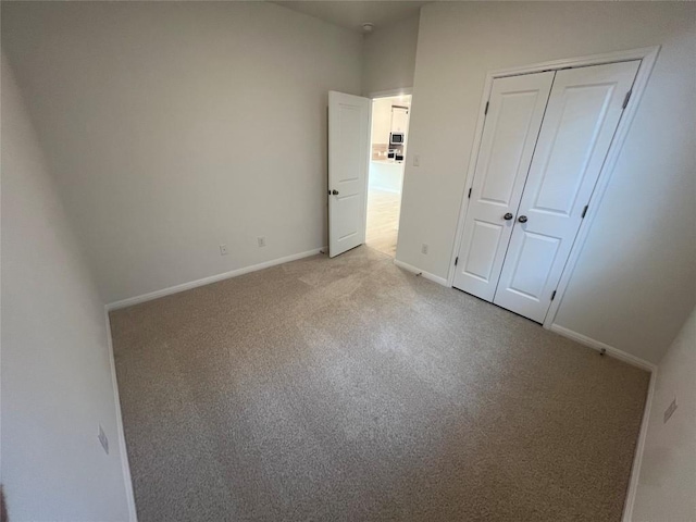 unfurnished bedroom with light carpet, a closet, and baseboards