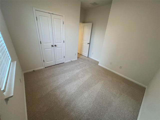 unfurnished bedroom with a closet, visible vents, baseboards, and carpet