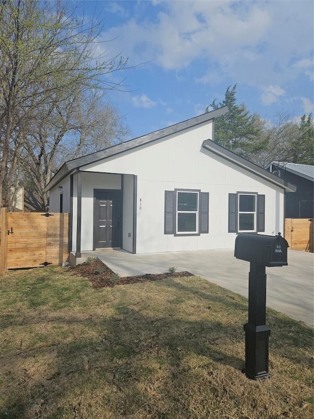 view of home's exterior with stucco siding, a lawn, and fence