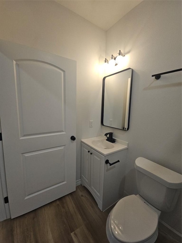 bathroom with toilet, wood finished floors, and vanity