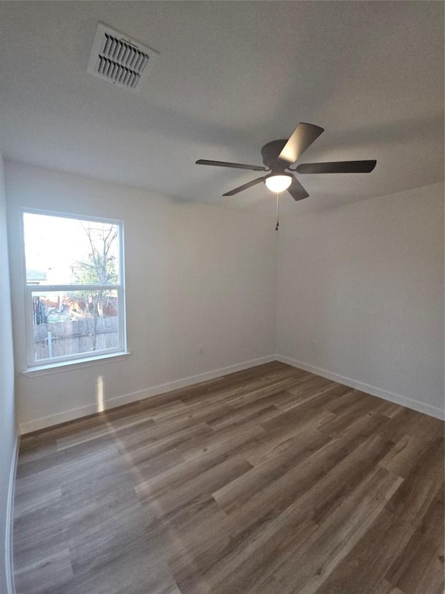 spare room featuring visible vents, baseboards, wood finished floors, and a ceiling fan