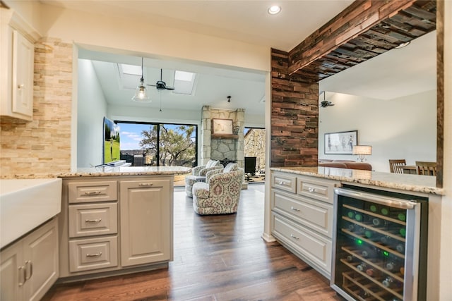 bar featuring beverage cooler, dark wood finished floors, beamed ceiling, decorative backsplash, and a stone fireplace