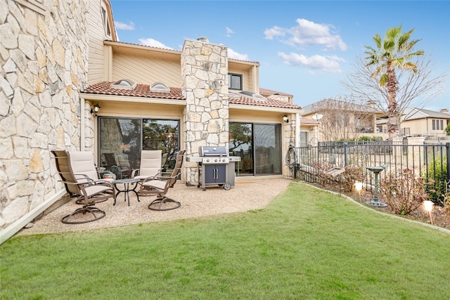 back of house featuring a patio, fence, a yard, a chimney, and a tiled roof