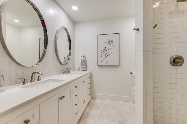 bathroom with a sink, baseboards, tasteful backsplash, and double vanity