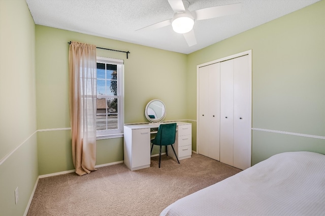 bedroom with a ceiling fan, a textured ceiling, a closet, baseboards, and light colored carpet