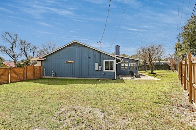 back of house featuring a patio, a lawn, board and batten siding, and a fenced backyard