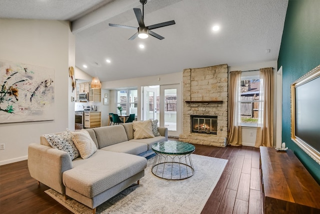 13202 Elysian Fields Cv, Austin, TX 78727 - living room with beamed ceiling, ceiling fan, dark wood-style flooring, a fireplace, and a textured ceiling
