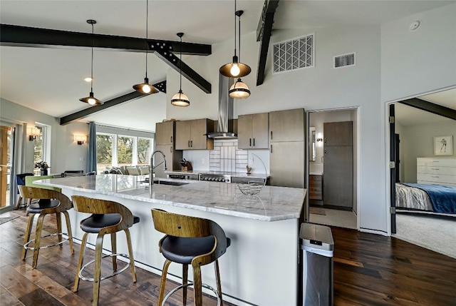 kitchen with beam ceiling, visible vents, wall chimney exhaust hood, and a sink