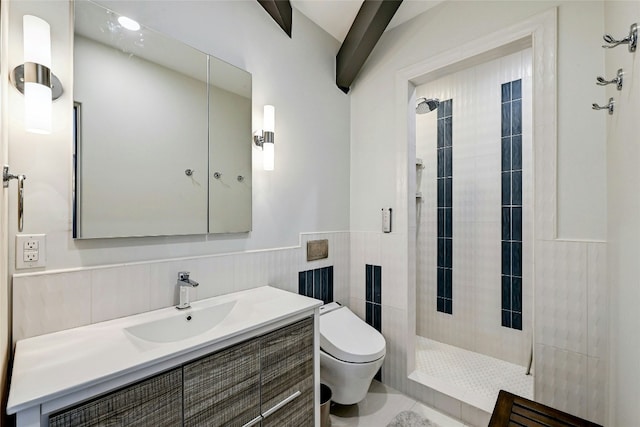 full bath with toilet, a tile shower, tile walls, wainscoting, and vanity