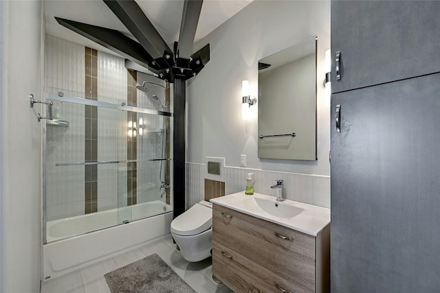 bathroom featuring tile patterned flooring, toilet, wainscoting, shower / bath combination with glass door, and vanity