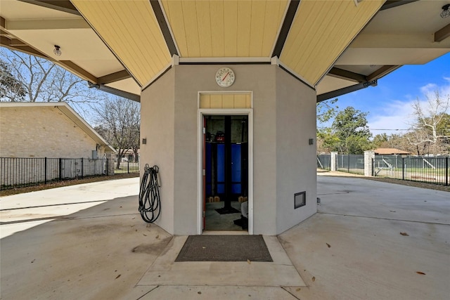 entrance to property featuring stucco siding, a patio, and fence