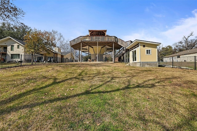 rear view of house featuring a wooden deck, stairs, a yard, and fence