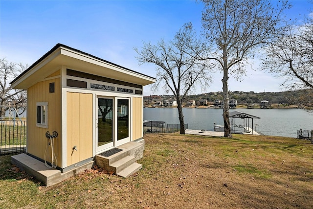 view of dock with a water view, a lawn, and fence