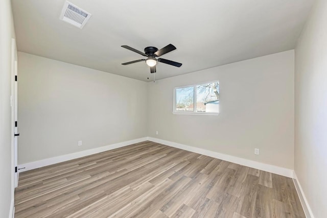 empty room with wood finished floors, baseboards, visible vents, and ceiling fan