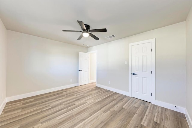 unfurnished room featuring a ceiling fan, light wood-style flooring, visible vents, and baseboards