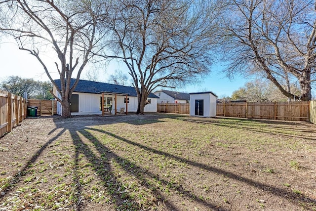 view of yard featuring an outbuilding, a storage unit, and a fenced backyard