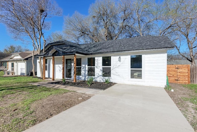 view of front facade featuring roof with shingles, a front lawn, and fence